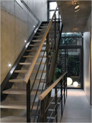 Fait de bois et dacier, lescalier repose sur une entrée en béton ciré MAPEI Ultratop gris argent, appliqué par A2M le Béton Design