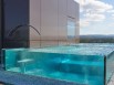 Une piscine aux parois de verre posée sur un toit