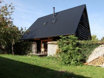 Une maison s'insère entre deux murs en pierres 