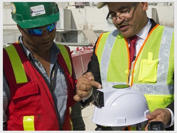 Deux ouvriers du Qatar découvrent le fonctionnement d'un casque "réfrigérant" 