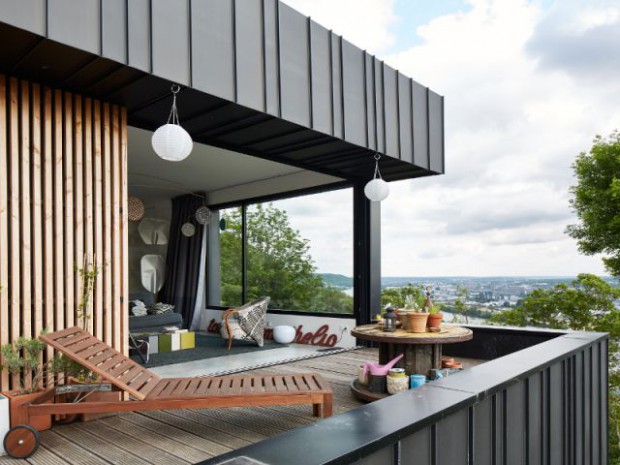 Une maison en zinc noir posée sur un mur en brique