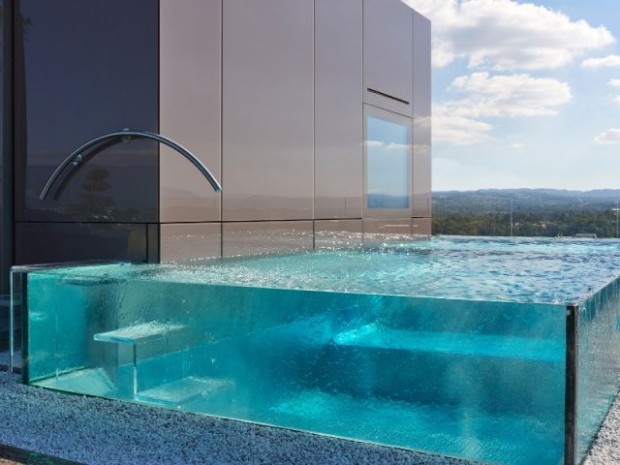 Une piscine aux parois de verre posée sur un toit
