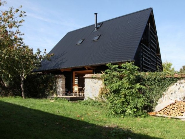 Une maison tout en bois blottie entre deux murs en pierres